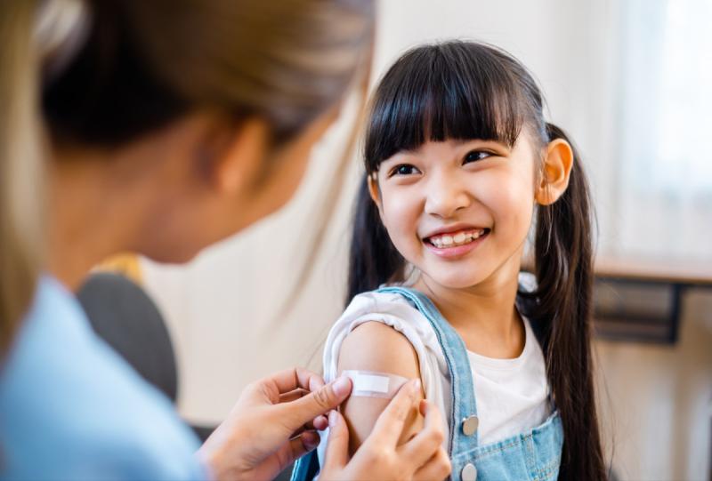 a child smiling as a doctor puts a bandaid on her arm